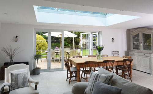 an open plan room with a dining table and large folding doors