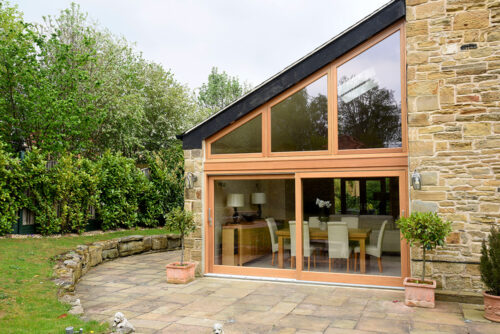 an oak stained set of sliding doors with a bespoke cut toplight