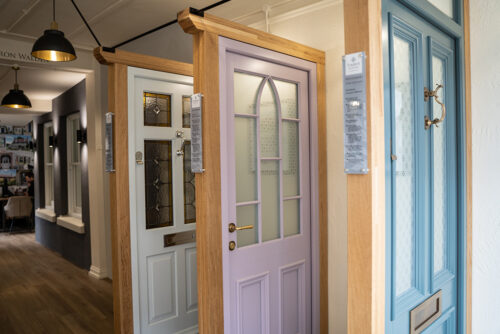 a set of 3 front doors including a bespoke pink sample, on display in a showroom