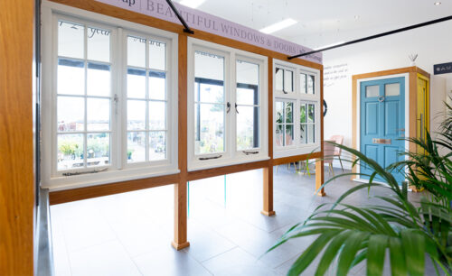 casement windows and a blue front door on display in a light open showroom