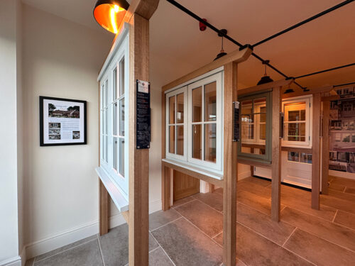 a series of casement windows in oak frames on display in a showroom