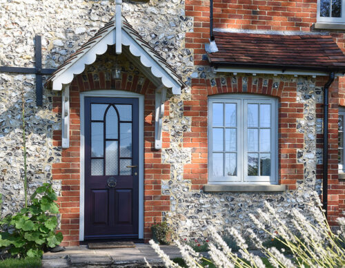 a dark gothic front door on a stone flint building