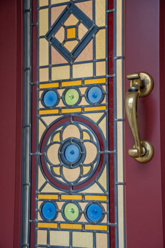 bespoke stained glass on a red front door with a brass doctors knocker