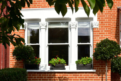 traditional victorian sash windows between stone mullions on a red brick home