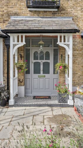 a beautiful ornate grey front door with etched glass, under a timber canopy