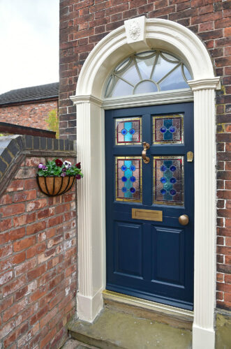 a deep blue front door with beautiful encapsulated stained glass