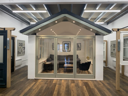 a set of bifold doors on display in a showroom, using a mock sun room appearance