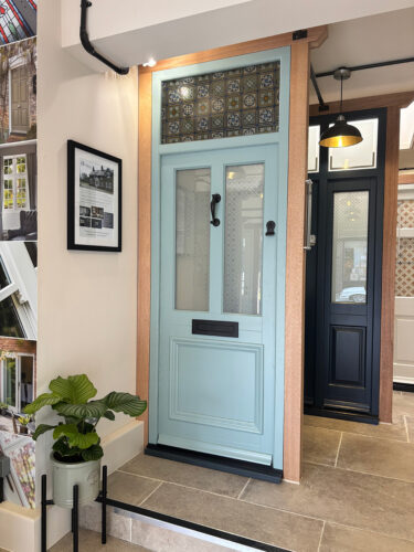 a blue door with a toplight between oak posts on display in a showroom