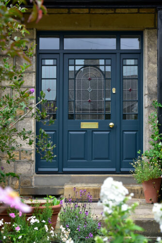 a dark blue front door with sidelights and toplight, with stained glass