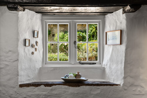 a white casement window in a rural farmhouse with oak beams
