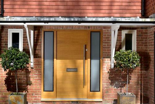 an oak stained contemporary front door with sidelights under a canopy