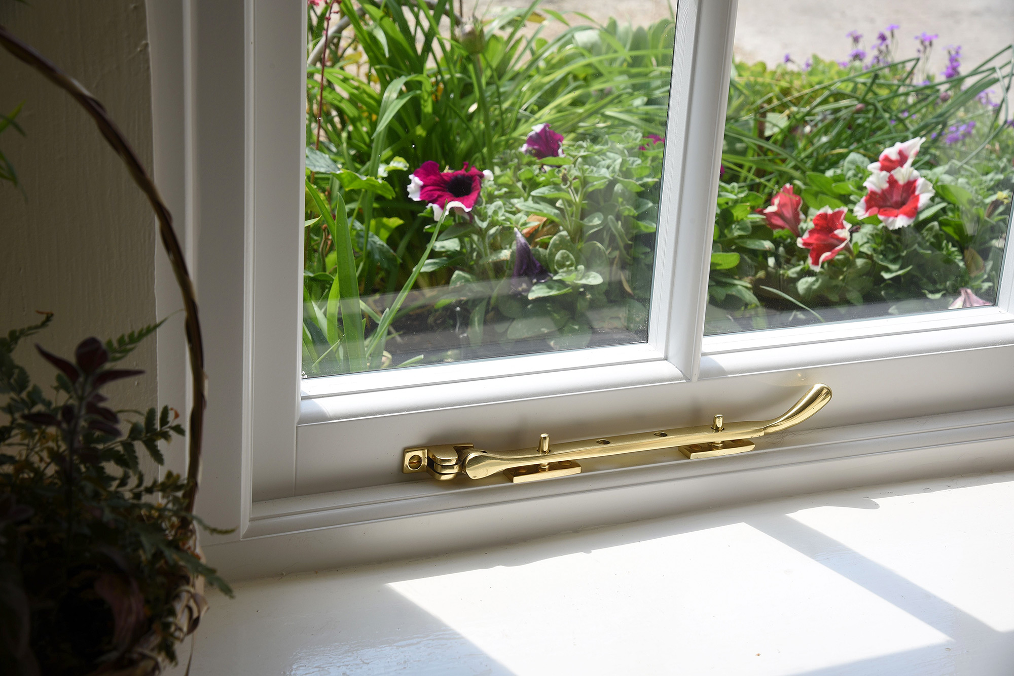 a brass pegstay on a white window