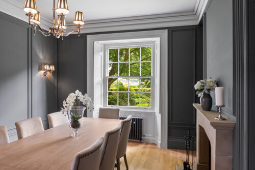 a beautiful dining room with dark wallpaper, and a white georgian sash window