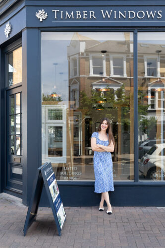 a lady in a blue dress stood in front of a timber windows showroom