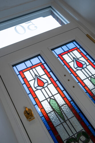 a white front door with red and blue stained glass