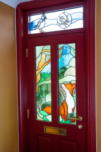a red front door with stained glass in the shape of animals