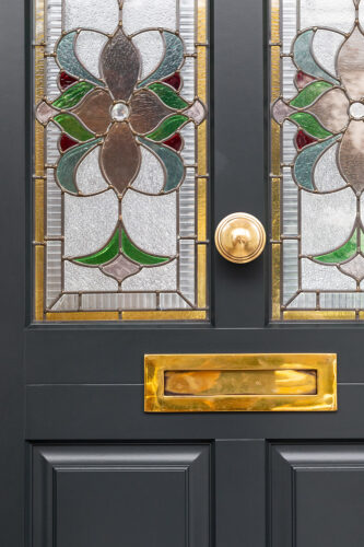 a dark front door with a vibrant and elaborate stained glass pattern