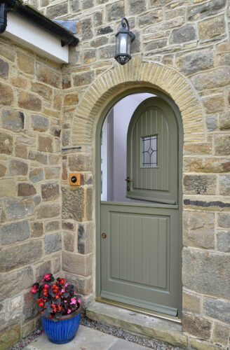 a deep green arched stable door on a stone property
