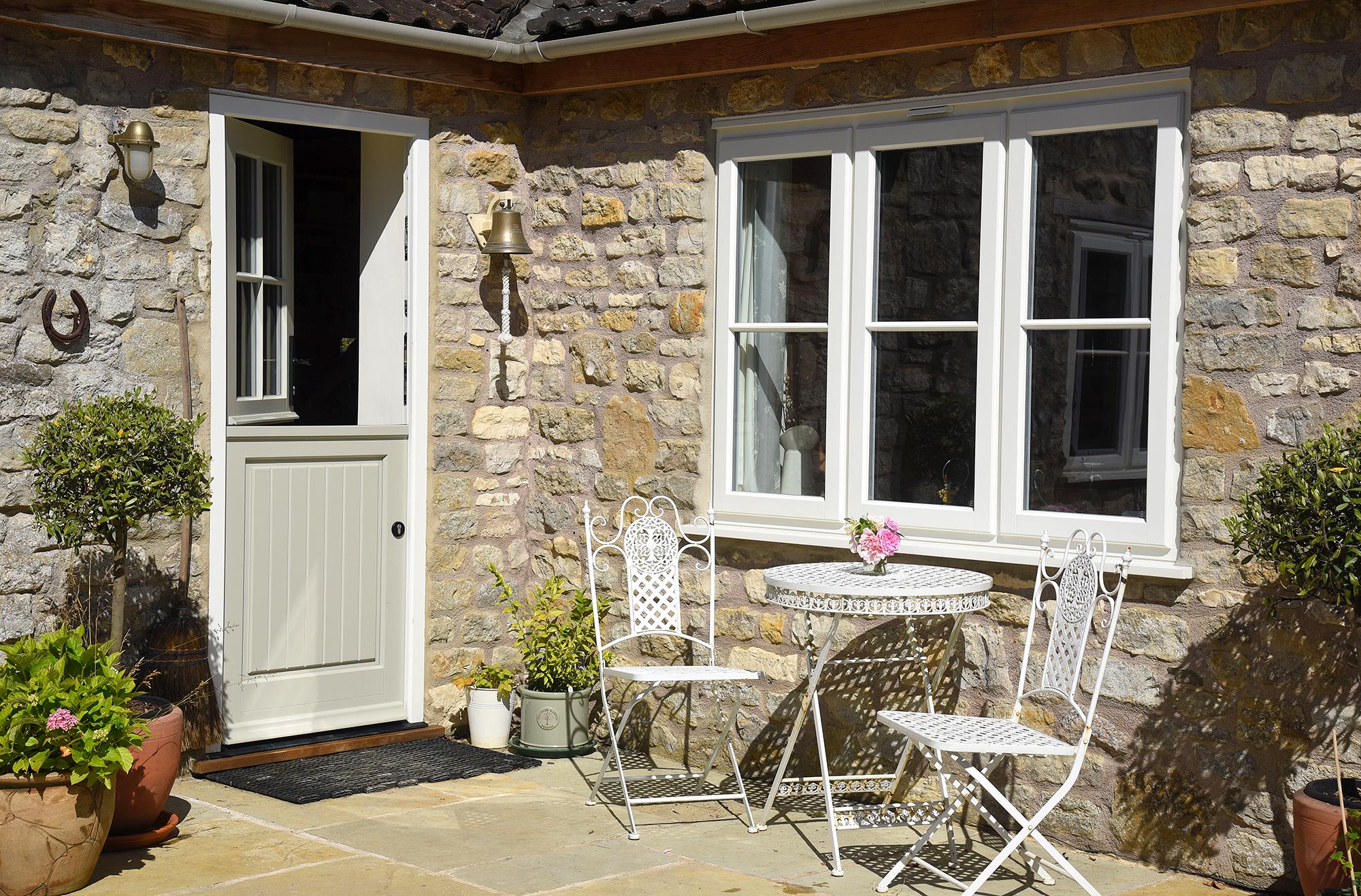 a partly open stable door next to a set of lipped casement windows