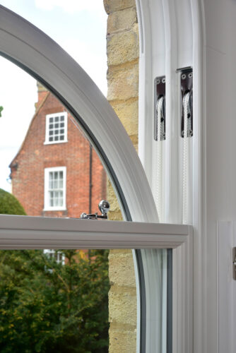 an arched sash window displaying the cords and weights operating mechanism