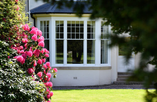 an edwardian sash bay window behind a beautiful blooming garden